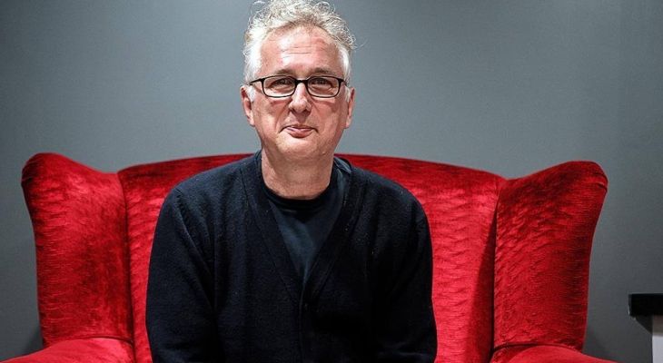 Henry Normal sitting on a red arm chair